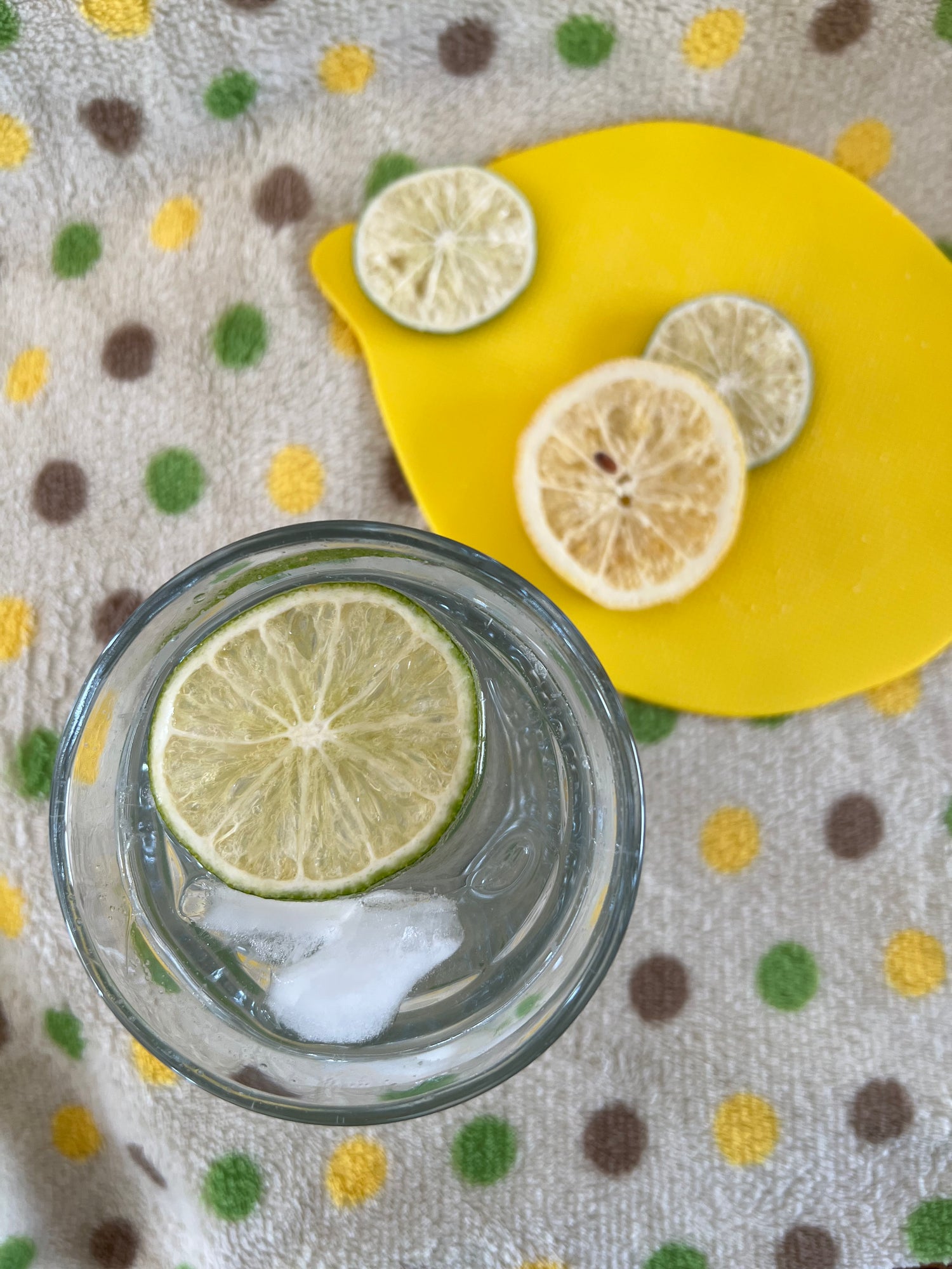 Top view glass of water with lime slice beside other lemon and lime slices