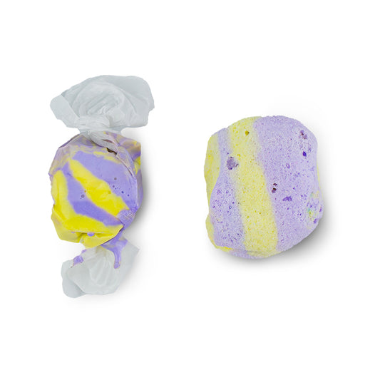 Purple and yellow freeze-dried salt water taffy piece beside regular paper wrapped taffy